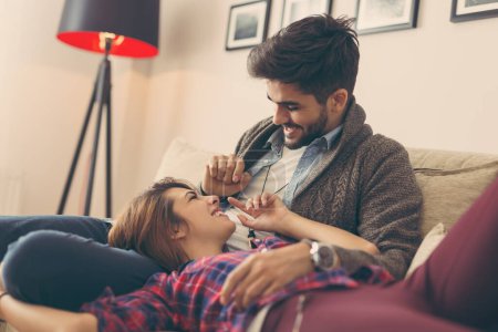 Photo for Couple in love relaxing at home lying on sofa in living room, cuddling and relaxing. Focus on the guy - Royalty Free Image