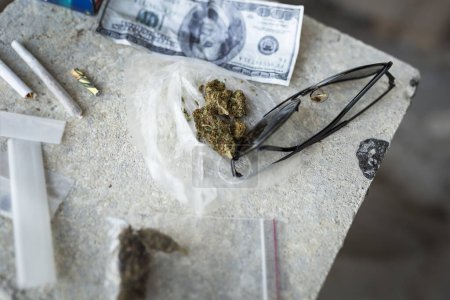 Foto de Vista de ángulo alto de las articulaciones enrolladas y los brotes de marihuana en una bolsa. Enfoque selectivo en la maleza en el medio - Imagen libre de derechos