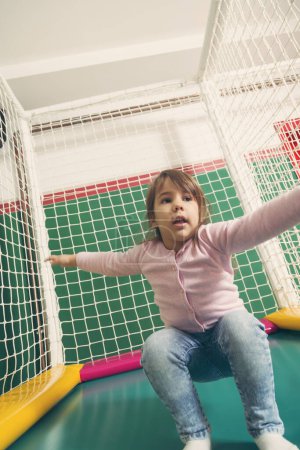 Foto de Alegre niño jugando en un trampolín en una sala de juegos - Imagen libre de derechos