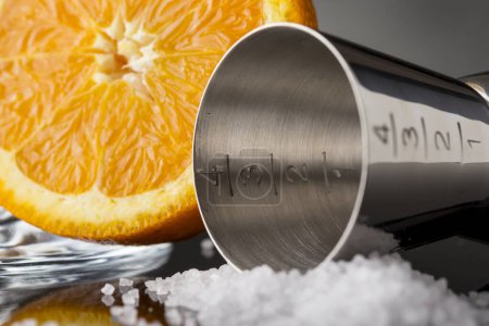 Téléchargez les photos : Détail d'un peu de sel, fruits à l'orange et cocktail jigger à côté. Focus sélectif sur l'échelle des nombres jigger - en image libre de droit