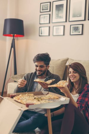 Photo for Couple in love eating pizza and having fun. Focus on the guy - Royalty Free Image