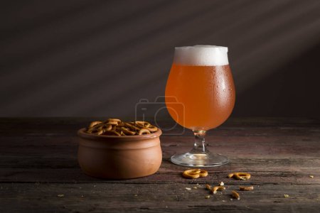 Photo for Glass of cold grapefruit beer and a bowl of pretzels on a rustic wooden table - Royalty Free Image