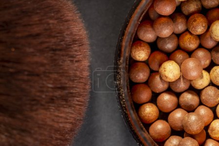 Photo for Close up of face powder pearls in an open powder box and a make up brush. Feminine cosmetics and make up product, bronzer and blusher. Focus on the bronzer pearls - Royalty Free Image