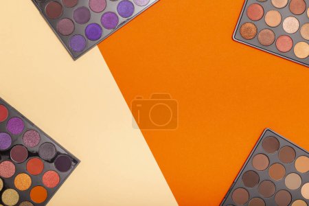 Téléchargez les photos : Pose plate de différentes palettes de fards à paupières sur fond coloré, avec espace de copie au milieu - en image libre de droit