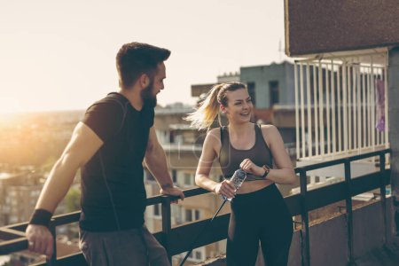 Photo for Young couple standing on a building rooftop terrace, getting ready for workout - Royalty Free Image