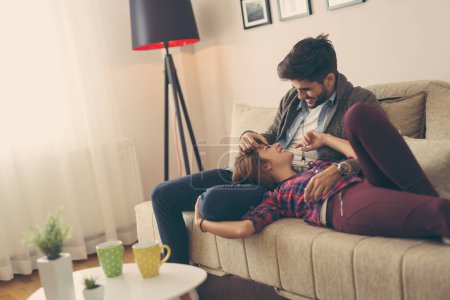 Téléchargez les photos : Couple amoureux se détendre à la maison couché sur le canapé dans le salon, câlins et détente - en image libre de droit