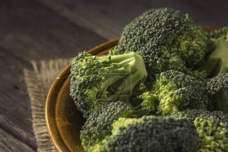 Photo for Bowl of fresh broccoli on a burlap coaster on rustic wooden table. Selective focus - Royalty Free Image