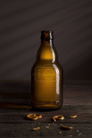 Foto de Botella de cerveza y algunos pretzels en una mesa de madera rústica - Imagen libre de derechos
