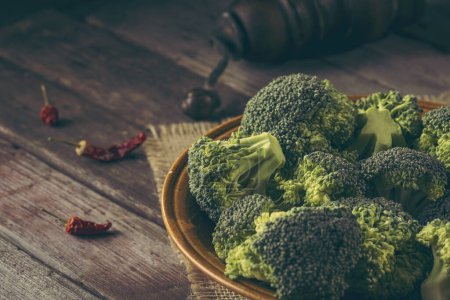 Photo for Bowl of fresh broccoli on a burlap coaster on rustic wooden table. Selective focus on the broccoli - Royalty Free Image
