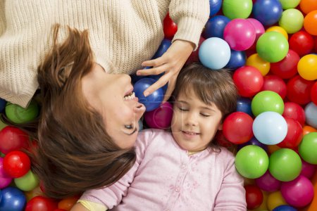 Photo for Top view of cheerful mother and daughter playing in a pool filled with colorful balls. Focus on the daughter - Royalty Free Image