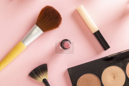 Foto de Mesa de plano superior de maquillaje, belleza y cosméticos productos aislados sobre fondo rosa. Maquillaje de pinceles, brillo de labios, lápiz labial y resaltador de cara paleta - Imagen libre de derechos