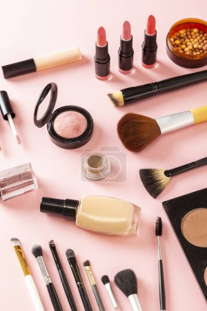 Photo for High angle view of various make up products on pink background. Make up brushes, blushes, face powders, highlighters, lip gloss, lipstick and glitters - Royalty Free Image
