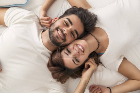 Téléchargez les photos : Vue du dessus d'un jeune couple amoureux couché au lit, câlin après le réveil - en image libre de droit