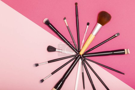 Téléchargez les photos : Pose plate de pinceaux de maquillage professionnels isolés sur fond rose - en image libre de droit