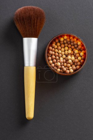 Photo for Flat lay of face powder pearls in an open powder box and a make up brush. Feminine cosmetics and make up products, bronzer and blusher. Selective focus on the bronzer pearls - Royalty Free Image