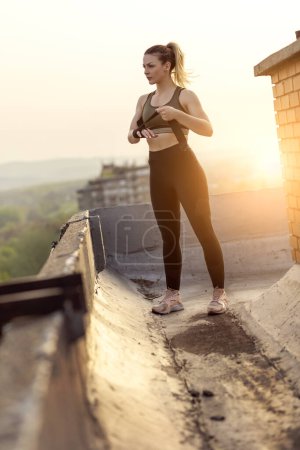 Téléchargez les photos : Femme enveloppant les mains avec des bandages avant l'entraînement sur un toit-terrasse de bâtiment - en image libre de droit
