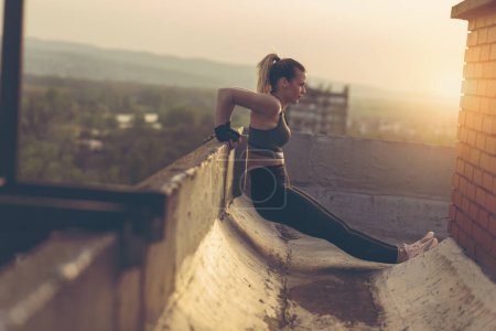 Téléchargez les photos : Belle femme en tenue de sport, travaillant sur un toit-terrasse de bâtiment - en image libre de droit