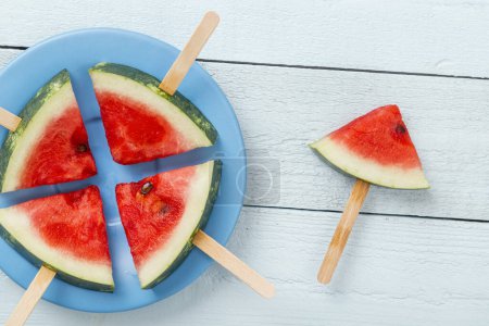 Photo for Table top shot of watermelon popsicles on a plate on rustic light blue wooden table - Royalty Free Image