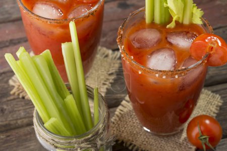 Photo for High angle view of a Bloody Mary cocktail with vodka, lemon and tomato juice, tabasco sauce and ice cubes decorated with celery leaves - Royalty Free Image