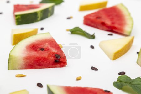 Téléchargez les photos : Vue en angle élevé des morceaux de pastèque et de melon, des feuilles de menthe et des graines de pastèque et de melon isolées sur fond blanc - en image libre de droit