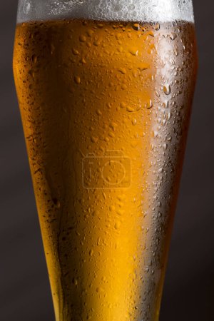 Photo for Close up of a wet glass of cold light beer with foam. Selective focus - Royalty Free Image