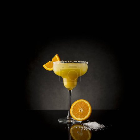 Photo for Orange margarita cocktail with tequila, triple sec, orange juice, crushed ice and some salt on the rim of a glass, decorated with a slice of orange - Royalty Free Image