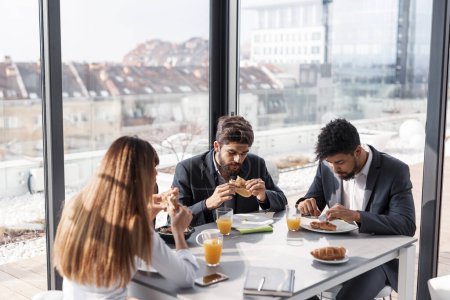 Foto de Grupo de gente de negocios desayunando en el restaurante de la compañía. Concéntrate en el hombre del medio - Imagen libre de derechos