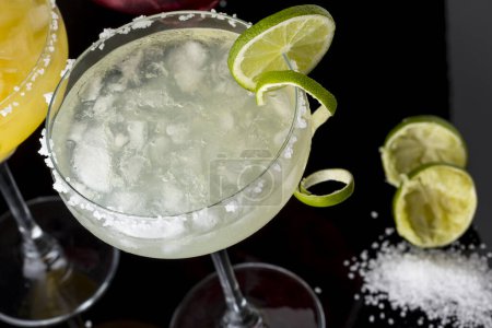 Photo for High angle view of a lime margarita cocktail with tequila, triple sec, lime juice, crushed ice and some salt on the rim of a glass, decorated with a slice of lime. Selective focus - Royalty Free Image