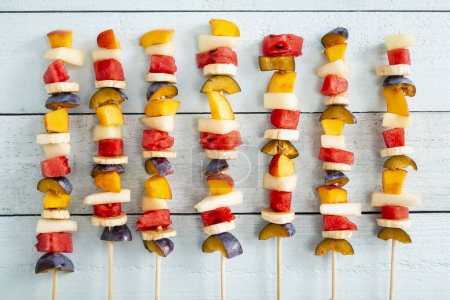 Photo for Top view of a cold colorful mixed fruit salad served on barbecue sticks as a summertime dessert - Royalty Free Image