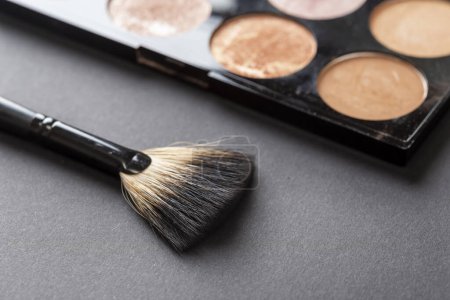 Photo for High angle view of face highlighter palette and a make up brush isolated on black background with copy space - Royalty Free Image
