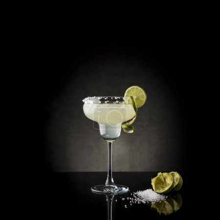 Téléchargez les photos : Cocktail classique de margarita au citron vert avec tequila, triple sec, jus de citron vert, glace concassée et un peu de sel sur le bord d'un verre, décoré avec une tranche de citron vert - en image libre de droit
