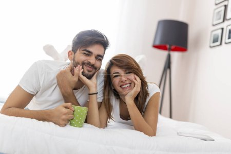 Téléchargez les photos : Amour couple câlins et boire du café après le réveil dans le lit - en image libre de droit