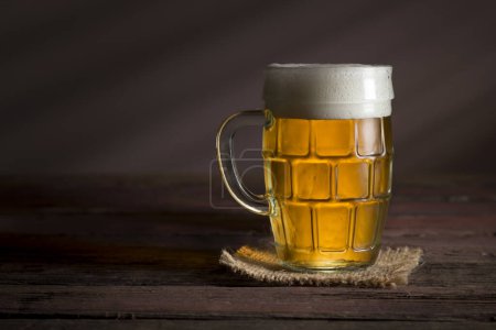 Téléchargez les photos : Tasse de bière froide et pâle posée sur une table en bois rustique - en image libre de droit