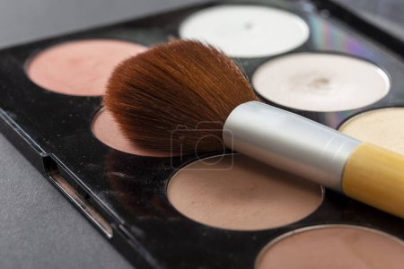 Photo for High angle view of face powder palette and a make up brush isolated on black background. Focus on the tip of the make up brush - Royalty Free Image
