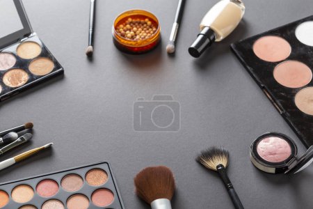 Téléchargez les photos : Vue grand angle de divers produits de maquillage sur fond coloré avec espace de copie. Brosses à maquiller, blush, poudres pour le visage, fards à paupières et surligneurs - en image libre de droit
