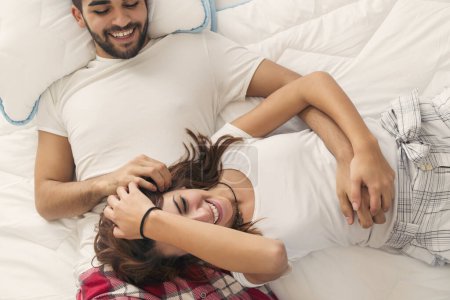 Téléchargez les photos : Vue du dessus d'un jeune couple amoureux couché au lit, câlin après le réveil - en image libre de droit