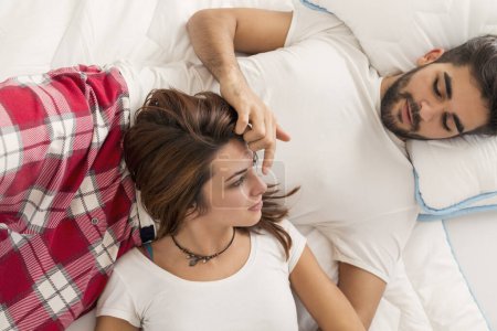 Téléchargez les photos : Vue du dessus d'un jeune couple amoureux couché au lit, câlin après le réveil. Concentre-toi sur la fille - en image libre de droit