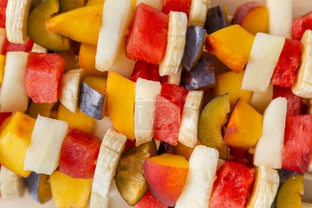 Foto de Ensalada de frutas mixtas coloridas servidas en palitos de barbacoa - Imagen libre de derechos