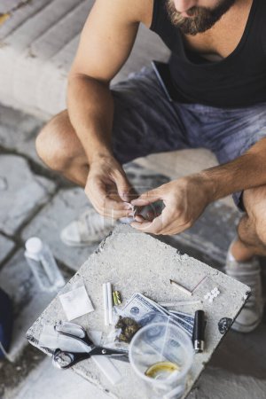 Foto de Detalle de las manos masculinas desempacando una cuchilla de afeitar para cortar una línea de heroína - Imagen libre de derechos