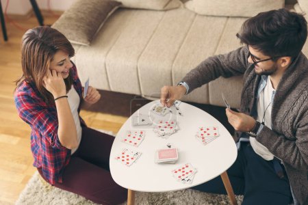 Foto de Vista de ángulo alto de la pareja sentada en el piso de la sala de estar junto a una mesa de café y divertirse jugando a las cartas. Concéntrate en la mujer - Imagen libre de derechos