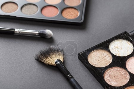 Photo for High angle view of an eyeshadow palette, highlighter palette, highlighter make up brush and an eyelid make up brush - Royalty Free Image