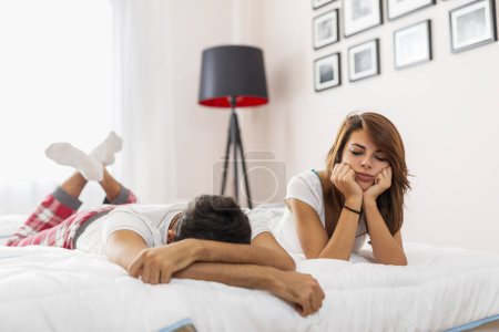 Photo for Young couple lying in bed, having an argument, sad and angry - Royalty Free Image