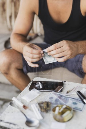 Foto de Drogadicto rodando billete de dólar para la heroína olfateando desde una pantalla de teléfono inteligente - Imagen libre de derechos