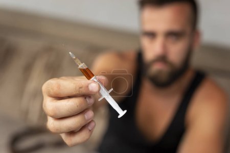 Foto de Consumidor de heroína intravenosa que ofrece heroína inyectable a otra persona; drogadicto que sostiene una jeringa de heroína - Imagen libre de derechos