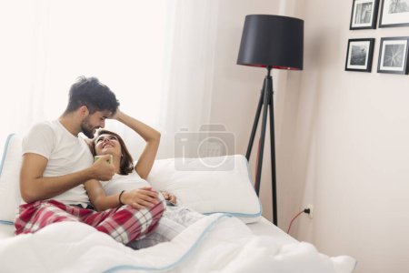 Téléchargez les photos : Amour couple câlins et boire du café après le réveil dans le lit - en image libre de droit