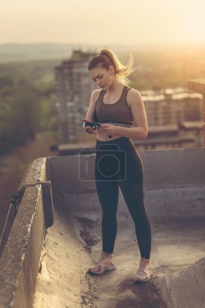 Téléchargez les photos : Femme enveloppant les mains avec des bandages avant l'entraînement sur un toit-terrasse de bâtiment - en image libre de droit