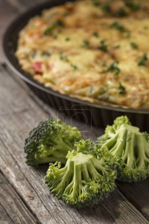 Photo for Fresh vegetable pie served on a cutting board on rustic wooden table. Selective focus on the broccoli - Royalty Free Image