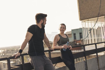 Téléchargez les photos : Jeune couple debout sur un toit-terrasse de l'immeuble, faire une pause d'entraînement - en image libre de droit