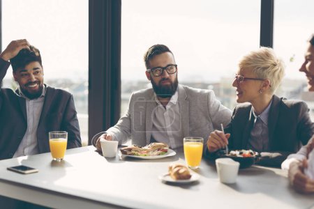 Photo for Group of business people having breakfast in company's restaurant. Focus on the man in the middle - Royalty Free Image
