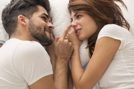 Foto de Vista superior de una pareja enamorada acostada en la cama una al lado de la otra, descansando y abrazándose - Imagen libre de derechos